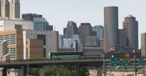 A Peter Pan Bus travels along a highway with the Boston skyline in the background, showcasing the company’s reliable motorcoach service throughout the Northeast.